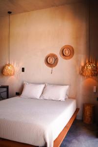 托多斯桑托斯Baja Temple的卧室配有一张白色床,墙上有2个篮子