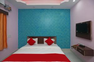 普里Goroomgo Savashi Puri的一间卧室配有一张带红色枕头的床和一台电视。