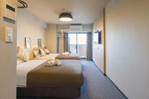大阪Apartment Hotel 11 Namba Minami III的酒店客房,设有两张床和一张沙发