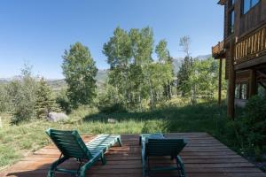 特柳赖德Adams Ranch Retreat by AvantStay Free Shuttle 2 Mountain Village Telluride Ski Resort的木甲板上摆放着两把绿色椅子