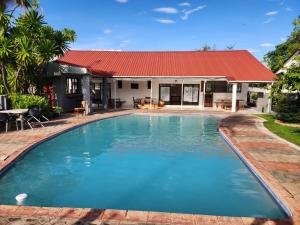 卢萨卡Mukala Lodge的一座红色屋顶房屋前的游泳池