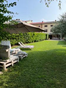 维罗纳Appartamento La Corte Verona的草坪配有躺椅和遮阳伞