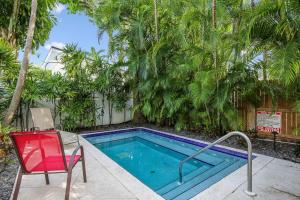 基韦斯特Paradise Place by AvantStay Key West Old Town Condo w Shared Pool的游泳池旁设有红色椅子和椅子