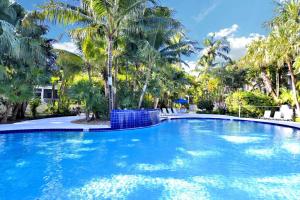 斯托克岛Coral Breeze by AvantStay Close to Beach w Balcony Shared Pool Month Long Stays Only的一个种有棕榈树的大型蓝色游泳池