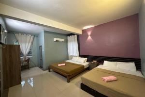 瓜埠Bull & Bear Airport Hotel Langkawi的一间卧室设有两张床和紫色墙壁