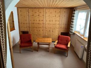 阿罗萨Chalet Baur的一间设有两把椅子、一张桌子、一张桌子和两把椅子的房间