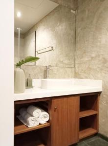 普吉镇Waterfront Suites Phuket by Centara NEW的浴室配有盥洗盆和带毛巾的台面。