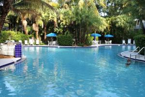 斯托克岛Paradise Point by AvantStay Golf Course Living的一座种植了棕榈树和蓝伞的大型游泳池