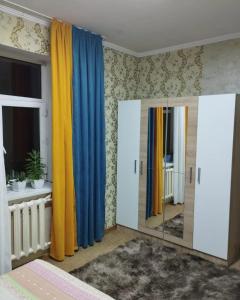 比什凯克Гостевой дом Энесай的一间卧室配有蓝色和黄色的窗帘和镜子
