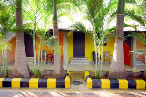亨比Megha Resort , Hampi的棕榈树前方的黄色房子