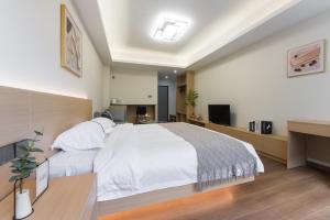 深圳WESU微宿服务公寓(深圳松坪山科技园店)的卧室配有一张白色大床和一张书桌