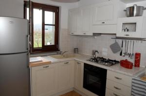 科尔托纳科尔托纳之窗乡村民宿的厨房配有白色橱柜和白色冰箱。