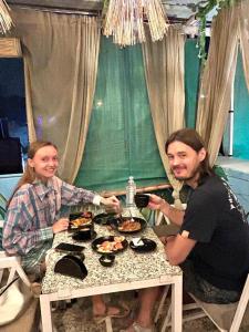 焦特布尔Shyam Hostel的坐在餐桌旁吃饭的男人和女人