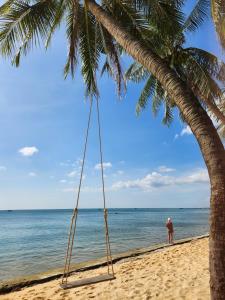 富国Mi Amor Luxury Island Apartment - 3 minutes to the beach的海滩上棕榈树上的秋千