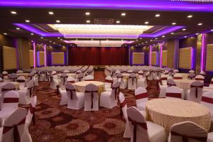 BoisarDAN Resorts & Weddings的一个带桌椅的大厅,位于一个紫色灯光的房间