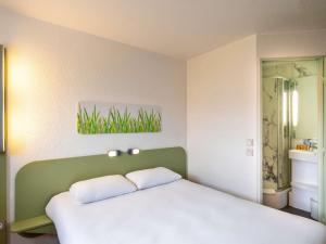 圣艾蒂安Ibis budget Saint-Étienne stade的一间卧室配有一张白色床和绿色床头板
