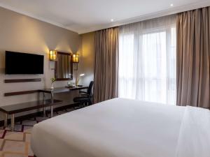 内罗毕Mercure Nairobi Upper Hill的一间酒店客房,配有一张白色的床和一张书桌