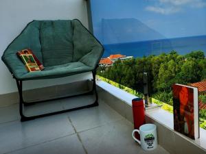 富国Mi Amor Luxury Island Apartment - 3 minutes to the beach的坐在阳台上的椅子上,边喝咖啡杯