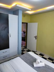 KisiiGreenstar Homes的一间卧室设有一张床、一台电视和一张棋盘地板