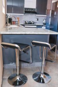 马塞卢Rental Flat in Maseru的厨房在柜台上设有两个吧台凳