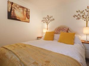 海尔舍姆Lavender Cottage的一间卧室配有一张带黄色枕头的床