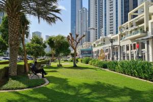 迪拜Manzil - 1BR in The Bay with Canal View nr Dubai Mall的坐在棕榈树公园长凳上的人