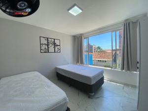 巴拉那州蓬塔尔Apartamento 1 quadra do mar的一间卧室设有两张床和大窗户