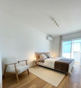 波尔蒂芒Sun Waves Beach Apartment的卧室配有床、椅子和窗户。