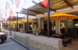 巴里代尔Barrydale Karoo Lodge - Boutique Hotel的餐厅设有黄色遮阳伞和木桌