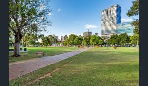 阿德莱德Hi 5 star Adelaide City Luxury Oasis的公园里长着长凳,树和建筑