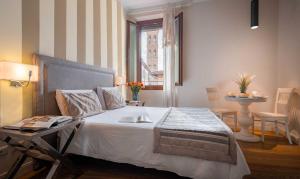 佛罗伦萨Boutique Hotel del Corso的一间卧室配有一张带桌子和窗户的床