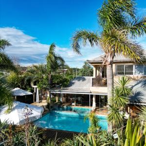 拉帕洛马Aloe Village Aparthotel & Spa的享有带游泳池和棕榈树的别墅的外部景色