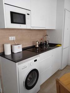 马德里Precioso apartamento recién reformado的厨房配有洗衣机和微波炉。