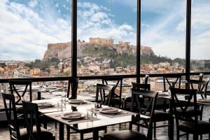 雅典Astor Hotel Athens的一间带桌椅的市景餐厅