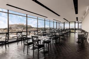 雅典阿斯图酒店的用餐室配有桌椅和大窗户