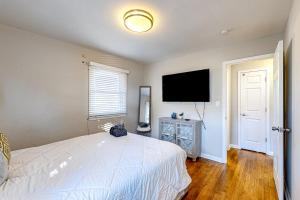 亚特兰大City Sanctuary的卧室配有白色的床和平面电视。
