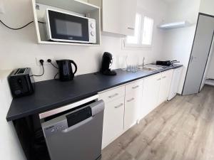 阿尔勒Auberge des Plaines - Appartements avec terrasse的厨房配有白色橱柜和黑色台面