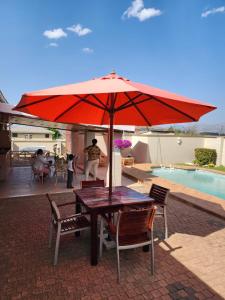科克斯塔德Majestic的游泳池旁的一张桌子和一把红伞