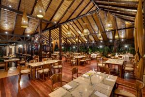 比加瓜Hideaway Rio Celeste Hotel的餐厅铺有木地板,配有桌椅