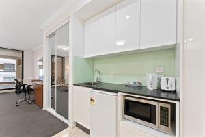 悉尼达令港APX公寓式酒店的厨房配有水槽和微波炉