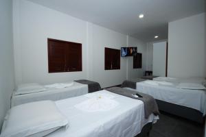 马塞约Pousada Girassol的客房设有三张床和一台平面电视。
