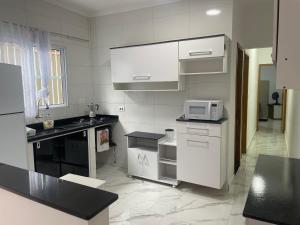 大普拉亚Casa novinha - Praia Grande - Mirim - 3 quadras da Praia Wi-Fi的厨房配有白色橱柜和微波炉