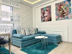 兹拉蒂博尔Apartmani SLEEP&JOY的客厅配有蓝色沙发和绘画作品