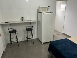 圣保罗Studio Zona norte SP - proximo Expo Center Norte Vila Guilherme的小厨房配有2张吧台凳和微波炉