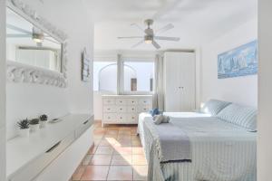科蒂略SunsetView apartment El Cotillo 2-4 personas的白色卧室配有床和吊扇