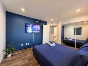 洛杉矶Trendy 2BR Near Hollywood Hotspots - BR9的一间卧室设有蓝色的墙壁,配有电视