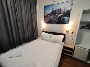 乌得勒支荷兰旅舍酒店的卧室配有一张白色床,墙上挂着一幅画
