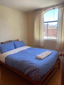 卡瓦纳科德Homestay Pachamama的一间卧室配有一张带蓝色床单的床和一扇窗户。