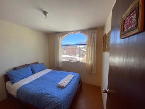 卡瓦纳科德Homestay Pachamama的一间卧室配有一张带蓝色棉被的床和窗户。