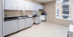 迪拜Greatest location Dubai的厨房配有白色橱柜、水槽和冰箱。